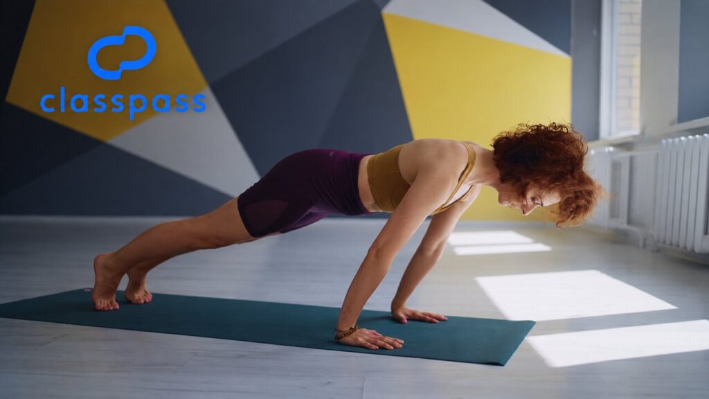 Woman holding a high plank on an exercise mat, with the blue ClassPass logo in the upper-left corner