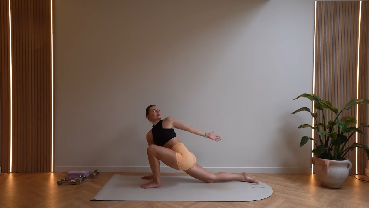 Woman in a Pilates pose on a mat inside a studio.